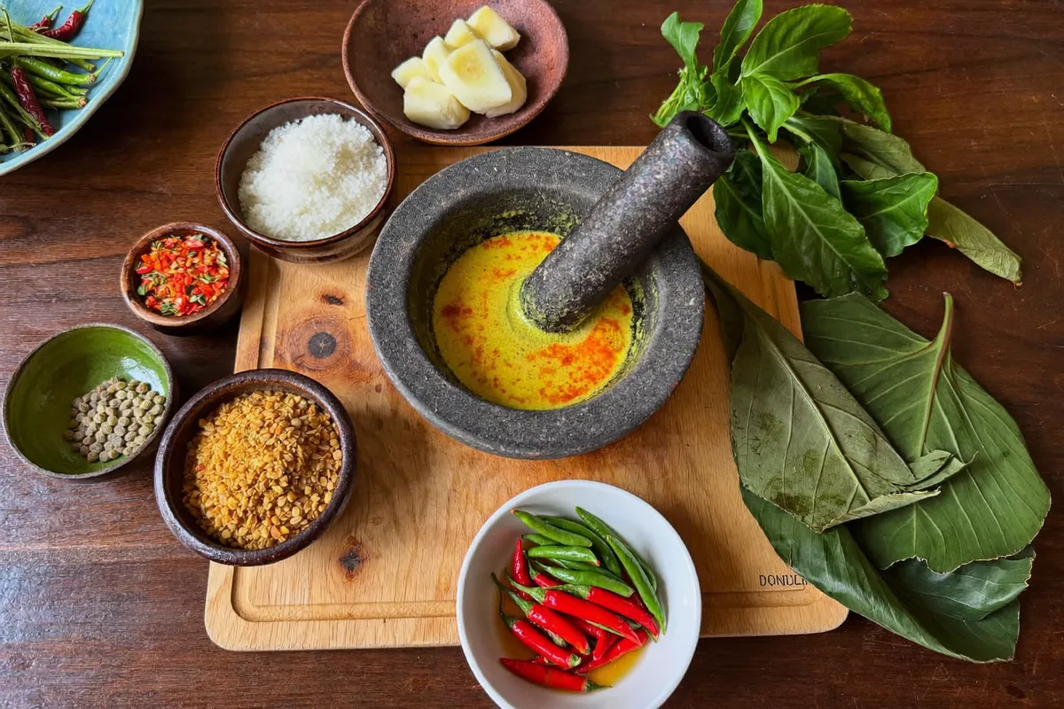 Guests grinding Balinese bumbu spice paste during a private cooking class in a Bali villa